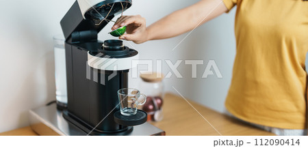 hand making Espresso Coffee by Coffee Maker Machine with Capsule of roasted coffee bean on wood table bar. Daily beverage drink at Home, Apartment and Office concept hand making Espresso Coffee by Coffee Maker Machine with Capsule of roasted coffee bean on wood table bar. Daily beverage drink at Home, Apartment and Office concept 112090414