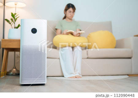 Air Purifier with woman read and relax on sofa. Purification system for filter and cleaning dust PM2.5 HEPA and virus in home. Allergy, Pure air, health lifestyle, Wellness life and Air Pollution Air Purifier with woman read and relax on sofa. Purification system for filter and cleaning dust PM2.5 HEPA and virus in home. Allergy, Pure air, health lifestyle, Wellness life and Air Pollution 112090448