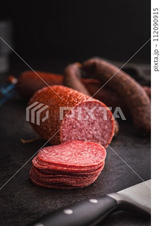 Sliced smoked salami sausages on black table. Sliced smoked salami sausages on black table. 112090915