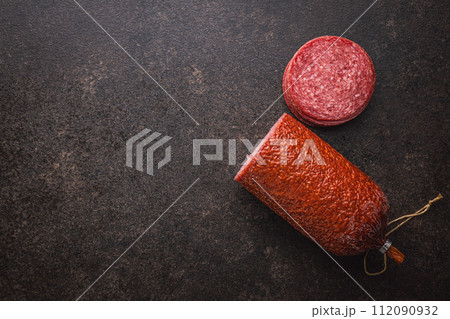 Smoked salami sausages on black table. Top view. 112090932