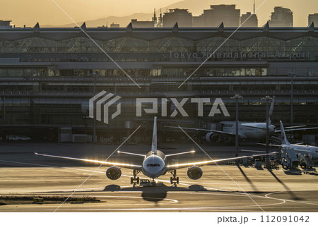 夕暮れの羽田空港　タキシング中の飛行機と第3ターミナル　東京都大田区 112091042