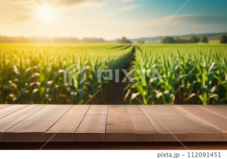 Empty wooden table, counter desk with blurred agricultural field background. Copy space for your promo, text or logo brand. Wood plank board, natural farming view. Blank tabletop, blur growing corn 112091451