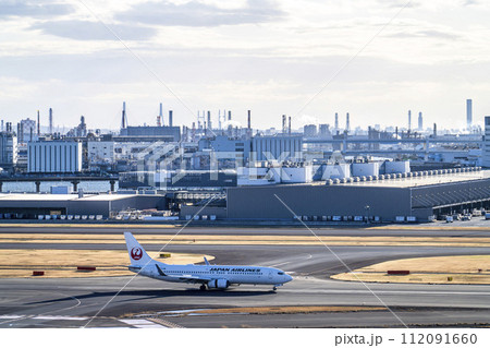 夕暮れの羽田空港　着陸した飛行機と工場群　東京都大田区 112091660