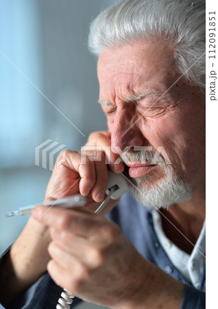 Portrait of sad sick senior man calling doctor 112091851