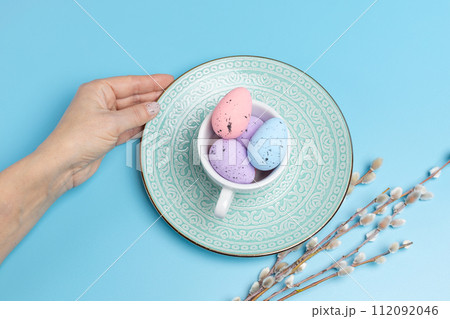 Cup with colored Easter eggs on the blue background. 112092046