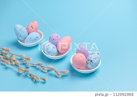 Saucers with colored Easter eggs on the blue background. 112092068