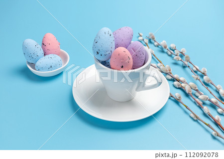 Cup with colored Easter eggs on the blue background. Cup with colored Easter eggs on the blue background. 112092078