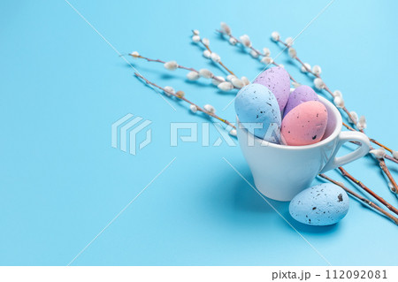 Cup with colored Easter eggs on the blue background. Cup with colored Easter eggs on the blue background. 112092081