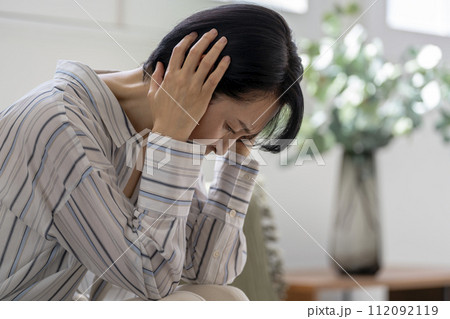頭を抱えたアラフィフの女性 112092119