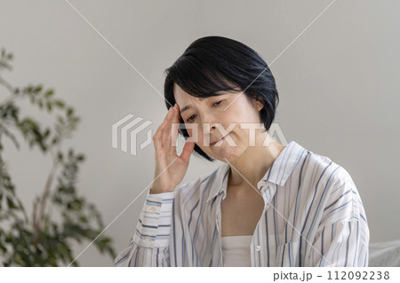 こめかみを押さえるアラフィフの女性 112092238