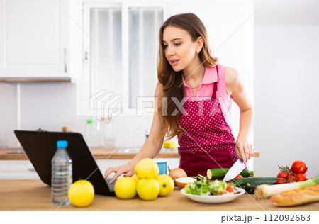 Woman cooking salad recipe from the Internet 112092663