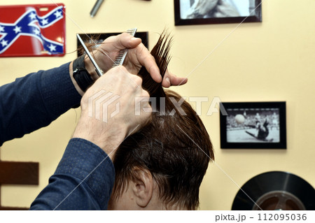Hairdresser cuts hair on a woman's head, side view. 112095036