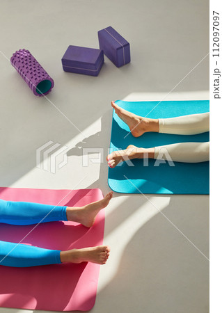 Two young women doing savasana pose after yoga class. Concept of physical and mental health care, deep meditation. 112097097