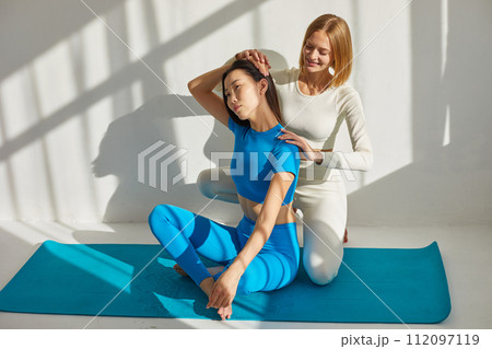 Yoga coach woman is teaching asian woman yoga and stretching. Concept of physical and mental health care, asian and caucasian ethnicity Yoga coach woman is teaching asian woman yoga and stretching. Concept of physical and mental health care, asian and caucasian ethnicity 112097119