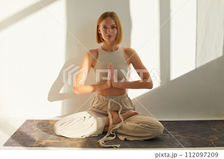 Woman practicing yoga and meditation in lotus pose on yoga mat, relaxed. Mindful meditation concept. Wellbeing Woman practicing yoga and meditation in lotus pose on yoga mat, relaxed. Mindful meditation concept. Wellbeing 112097209