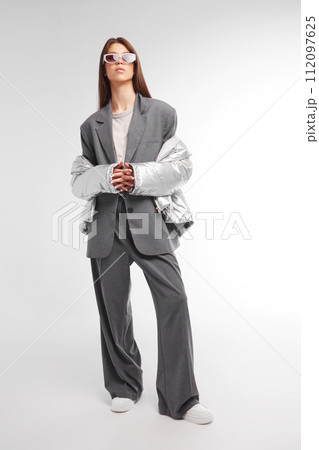 Fashion asian female model in silver down jacket and grey suit. Fashion asian female model in silver down jacket and grey suit. 112097625