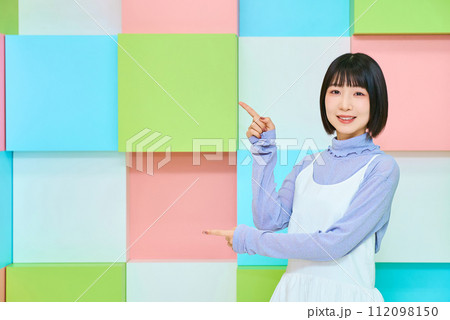 指差しのポーズをする若い女性とカラフルな背景 指差しのポーズをする若い女性とカラフルな背景 112098150
