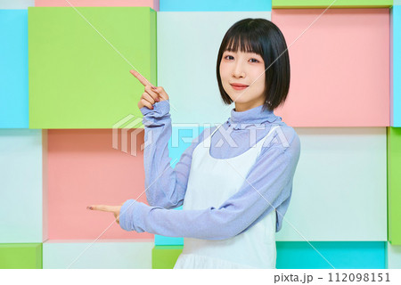 指差しのポーズをする若い女性とカラフルな背景 112098151