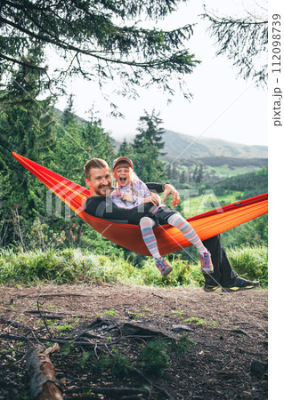happy father with daughter on hammock mountains on background 112098739