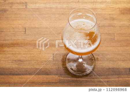 Craft beer in tulip glass on wooden table Craft beer in tulip glass on wooden table 112098968