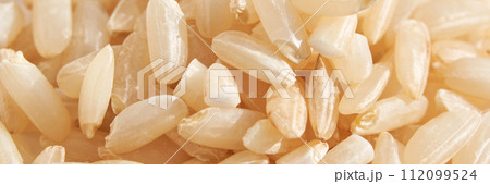 A background of dry brown rice grains showcases the integral, uncooked texture A background of dry brown rice grains showcases the integral, uncooked texture 112099524