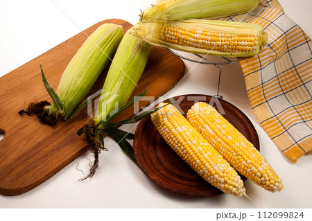 Clay plate with several cobs sweet corn on white wooden background.. 112099824