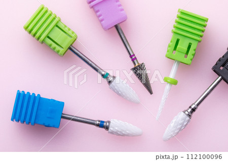 Five different cutters for hardware manicure and pedicure on a colored pink background, top view 112100096