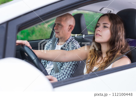 Confident young woman driving car with man in passenger seat Confident young woman driving car with man in passenger seat 112100448