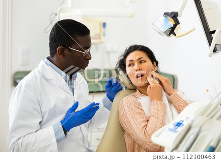 Asian woman suffering from toothache and talking about treatment with dentist Asian woman suffering from toothache and talking about treatment with dentist 112100463