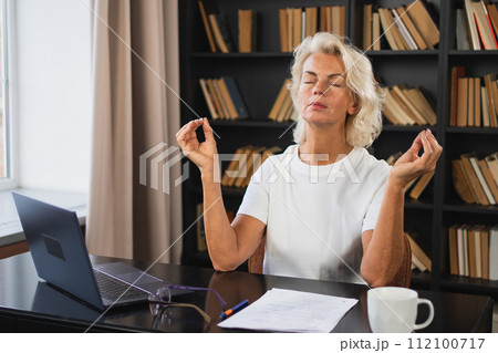 Yoga mindfulness meditation No stress keep calm. Middle aged woman practicing yoga at office. Woman taking break from work meditating relaxing. Mature lady doing breathing practice online yoga at work Yoga mindfulness meditation No stress keep calm. Middle aged woman practicing yoga at office. Woman taking break from work meditating relaxing. Mature lady doing breathing practice online yoga at work 112100717