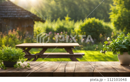 An empty wooden table in the foreground, with a blurred country house in the background against a verdant garden setting An empty wooden table in the foreground, with a blurred country house in the background against a verdant garden setting 112101048