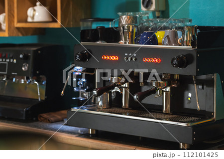 Professional black coffee machine stands on a desk Professional black coffee machine stands on a desk 112101425