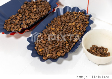 Samples of roasted arabica coffee grains are in plastic trays, close-up 112101428