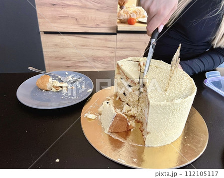 Female hands cut off a piece of festive cake with a knife 112105117