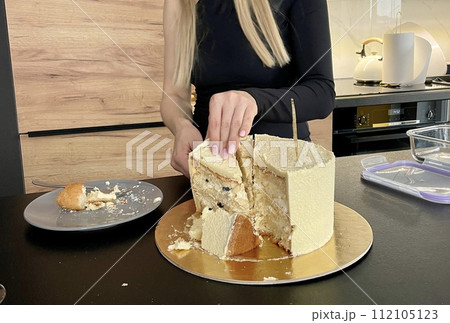 Female hands cut off a piece of festive cake with a knife 112105123