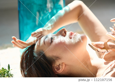 日差しを浴びて横たわる女性 112107156