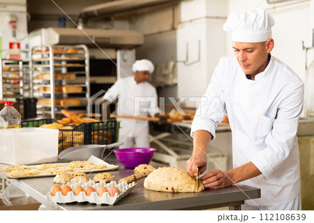 Baker makes buns and other sweet pastries from dough Baker makes buns and other sweet pastries from dough 112108639