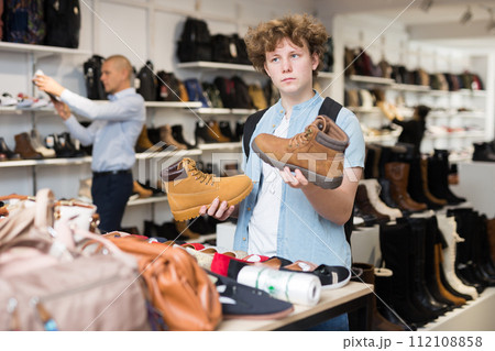 Positive teenager looking for winter casual boots at shopping mall Positive teenager looking for winter casual boots at shopping mall 112108858