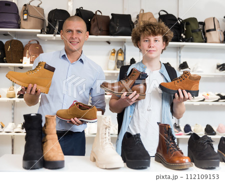 Cheerful father and son playing with shoes in shoe store 112109153