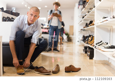Handsome man trying on summer brown shoes in shoe store 112109163