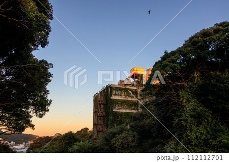 夕陽を受ける趣あるホテルの廃墟。古くからの歴史あふれる下田公園。  静岡県伊豆半島下田市。 2023 112112701
