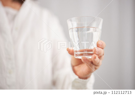水の入ったグラスを持つミドル女性の手元 水の入ったグラスを持つミドル女性の手元 112112713