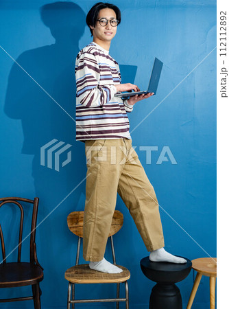 ブルーバックで椅子に立って作業する若い男性 112112892