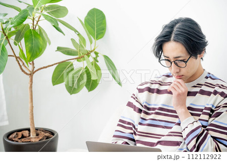 部屋で仕事をする若い男性 112112922