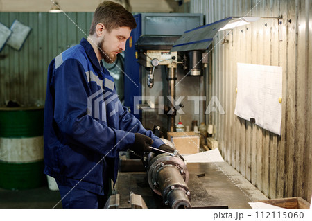 Medium side view shot of young man doing metalwork in factory workshop, copy space Medium side view shot of young man doing metalwork in factory workshop, copy space 112115060