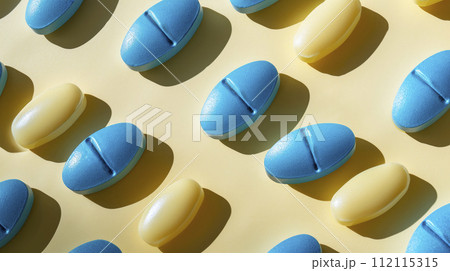 Yellow and blue color pills scattered on a yellow background, close-up. 112115315