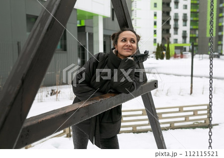 Young pretty woman in a winter jacket enjoying the weather while walking on the playground 112115521