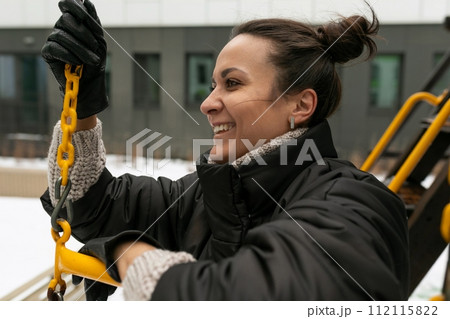 Young pretty woman in a winter jacket walking on the playground Young pretty woman in a winter jacket walking on the playground 112115822
