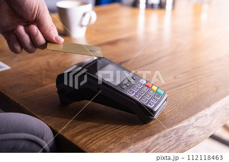 NFC credit card payment. Woman paying with contactless credit card with NFC technology. Wireless money transaction. Card machine in male hand on sunlight background 112118463