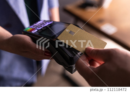 NFC credit card payment. Woman paying with contactless credit card with NFC technology. Wireless money transaction. Card machine in male hand on sunlight background 112118472